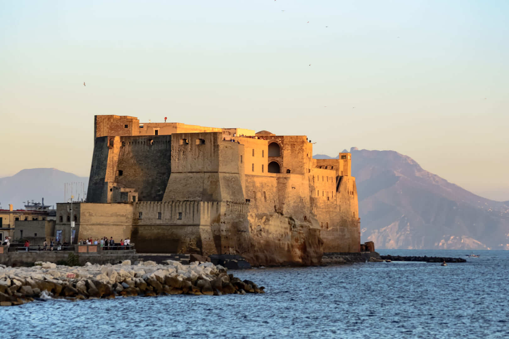 Vue paysage du golfe de Naples en Italie avec un château médiéval au premier plan, un point de repère de la ville, devant les montagnes au loin, bonne journée avec un temps parfait au coucher du soleil